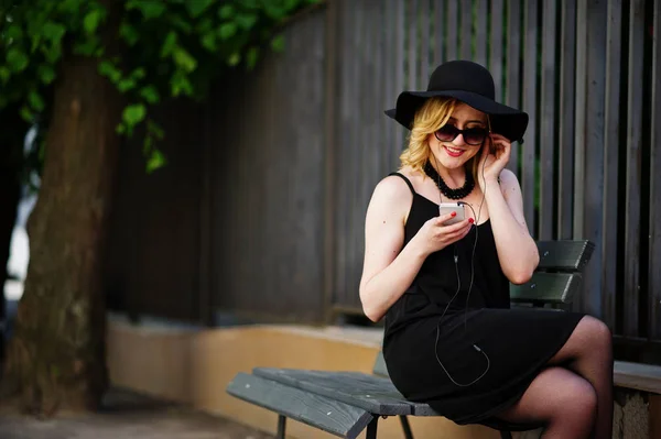 Блондинка в черном платье, солнцезащитные очки, ожерелья и шляпа ситти — стоковое фото