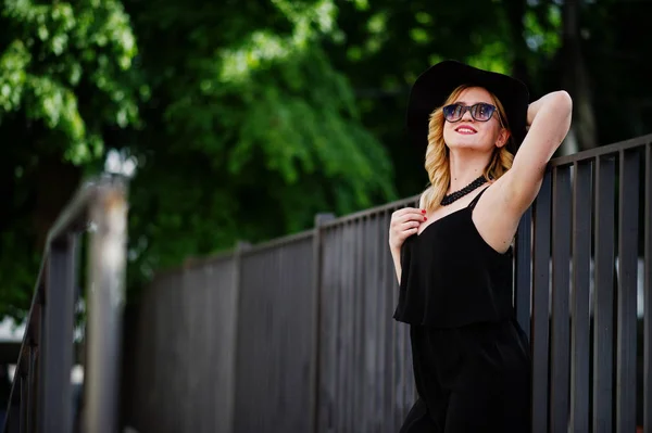 Блондинка в черном платье, солнцезащитных очках, ожерельях и шляпе — стоковое фото