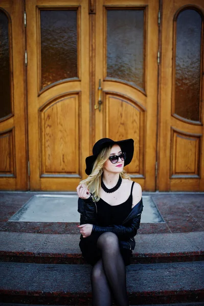 Femme blonde sur robe noire, veste en cuir, lunettes de soleil, cou — Photo