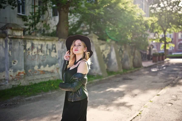 Mulher loira em vestido preto, jaqueta de couro, colares e chapéu p — Fotografia de Stock
