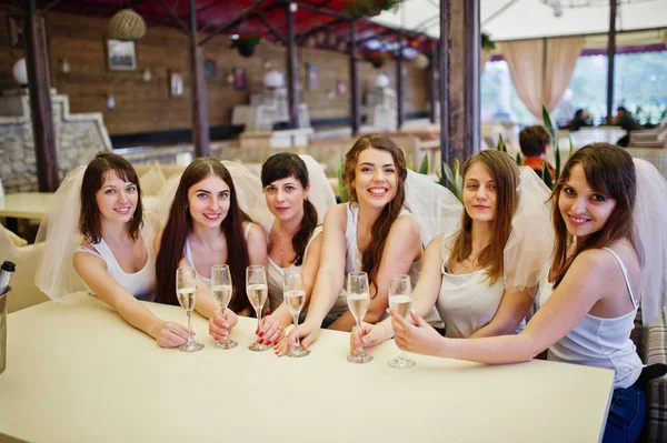 Grupo de chicas alegres en camisas blancas sentadas a la mesa y dri —  Fotos de Stock