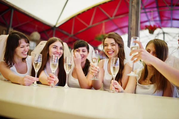 Grupo de meninas alegres em camisas brancas sentadas à mesa e dri — Fotografia de Stock