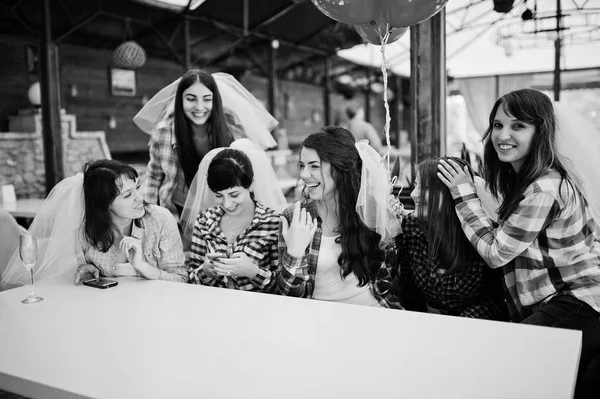 Groupe de filles gaies à carreaux chemises assises à table sur — Photo