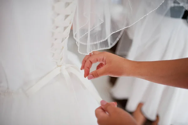 Brautjungfer hilft einer Braut, eine Schleife an einem Brautkleid zu binden. — Stockfoto