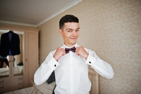 Groom tie his bow tie at room. — Stock Photo, Image