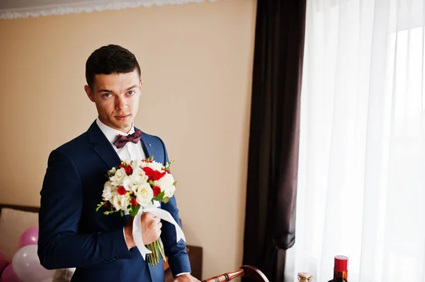 Portrait of a handsome groom standing in the room next to a wind — Stock Photo, Image