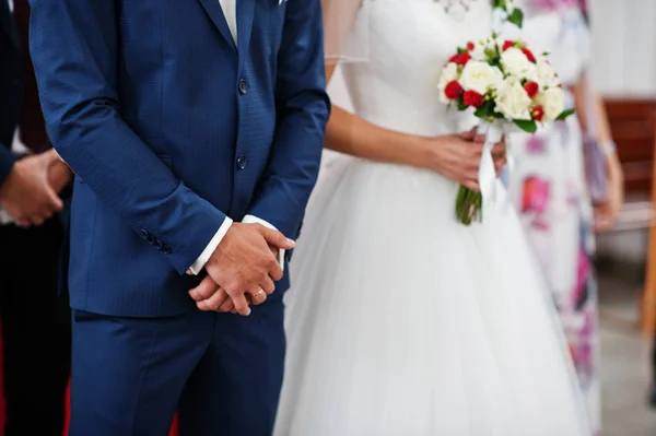 Bride holding a bouquet and groom crossing his hands stand in th — Stock Photo, Image