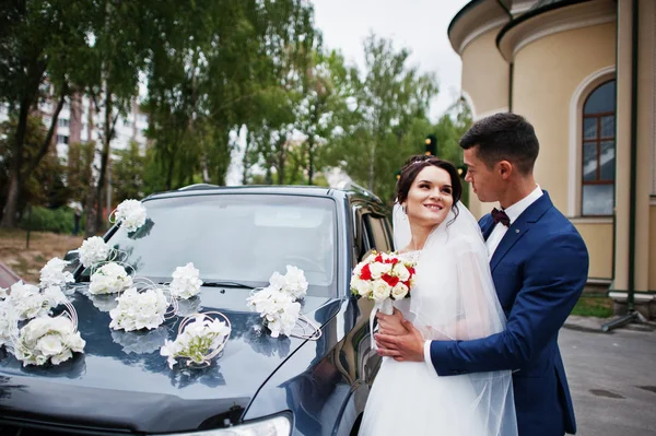 Hochzeitspaar steht draußen neben dem kühl dekorierten Auto — Stockfoto