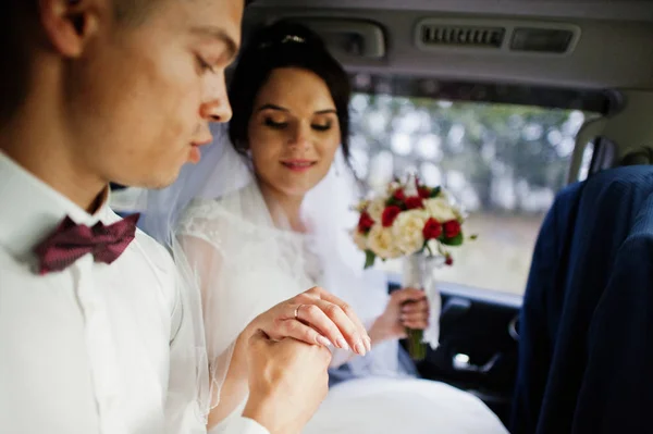 Pareja de boda sentada dentro de un coche moderno. Mirando cada uno o — Foto de Stock