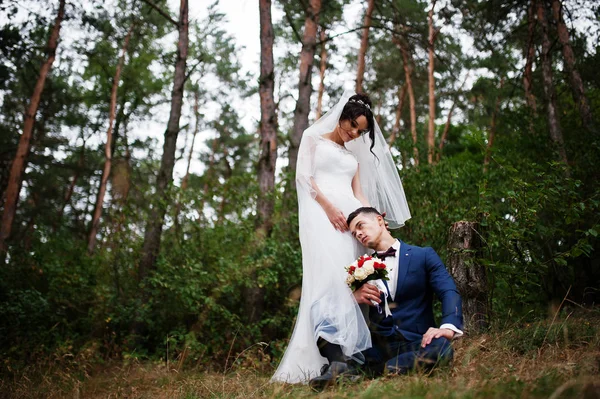 Makellose Braut im Stehen und ihr Mann, der neben ihr im T sitzt — Stockfoto