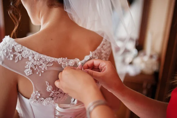 Bridesmaid helping to tie a ribbon on a wedding dress in a spaci