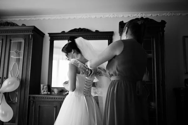 Dama de honra ajudando a amarrar uma fita em um vestido de noiva em um espaço — Fotografia de Stock