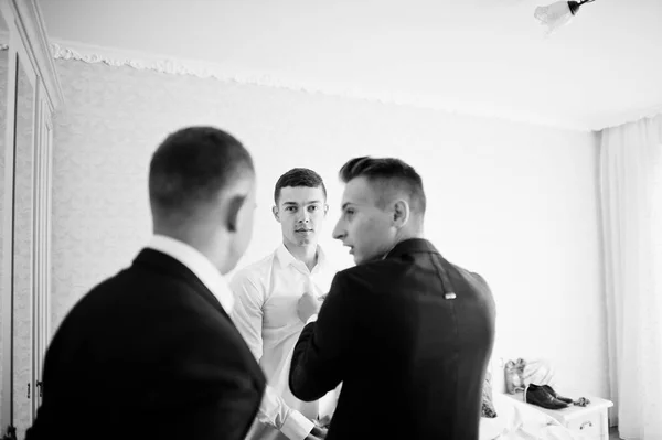 Groomsmen helping groom to dress up and get ready for his weddin — Stock Photo, Image