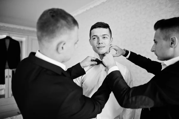 Groomsmen helping groom to dress up and get ready for his weddin — Stock Photo, Image