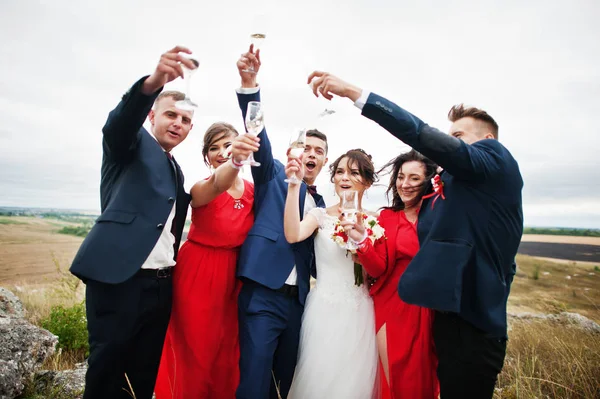 Bruidspaar en braidsmaids met groomsmen drinken champagne — Stockfoto