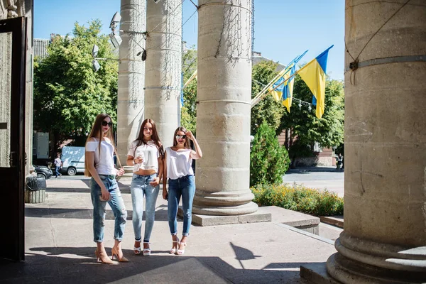 Tres hermosas chicas de pie junto a las columnas en un día soleado . —  Fotos de Stock