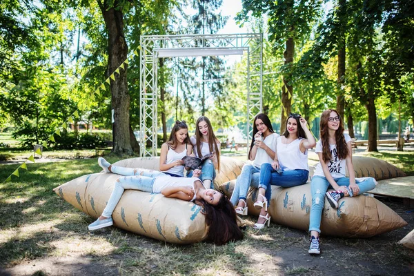 Sechs junge glückliche Mädchen haben Spaß auf riesigen Kissen im Park. — Stockfoto