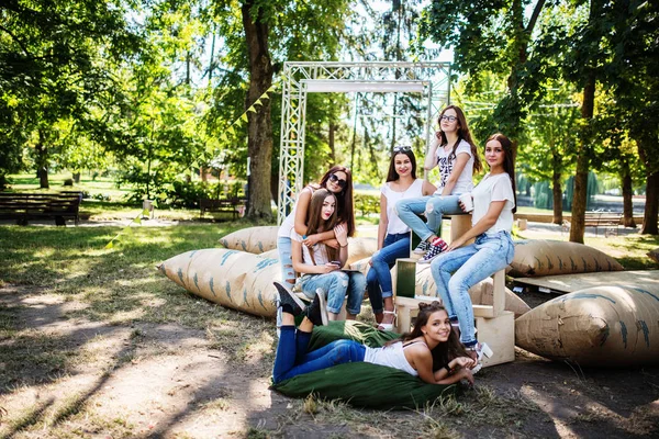 Sechs junge glückliche Mädchen haben Spaß auf riesigen Kissen im Park. — Stockfoto