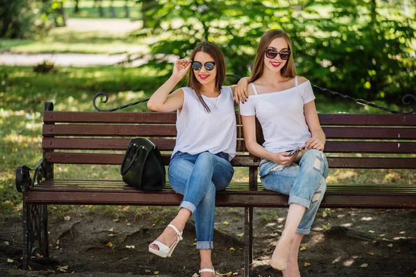 İki muhteşem kız parkta bankta oturmuş. — Stok fotoğraf