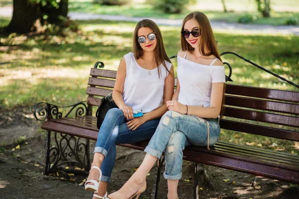 Due favolose ragazze sedute sulla panchina nel parco . — Foto Stock