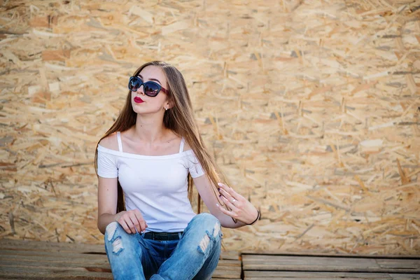 Retrato de una hermosa chica sentada en tablas de madera contra ve —  Fotos de Stock