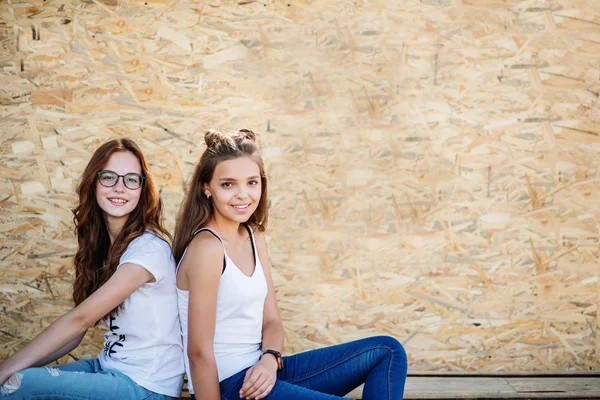 Retrato de una hermosa chica sentada en tablas de madera contra ve —  Fotos de Stock