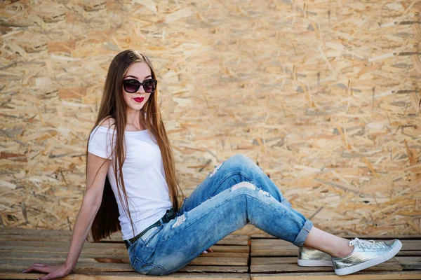 Retrato de uma bela menina sentada em tábuas de madeira contra ve — Fotografia de Stock