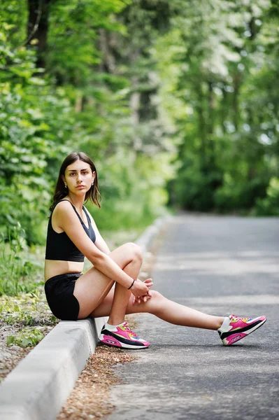 Deportiva en ropa deportiva descansando en un parque verde después del tren — Foto de Stock