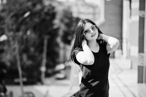Brunett tjej på svart klänning, solglasögon poserar på gatan av cit — Stockfoto