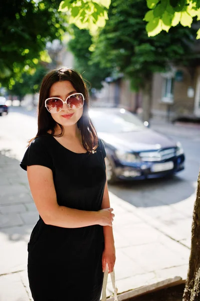 Brunette fille d'affaires à robe noire sur lunettes de soleil avec sac à main — Photo