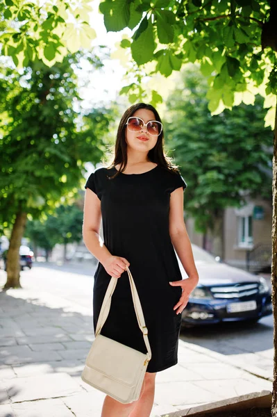 Morena chica de negocios en vestido negro en gafas de sol con bolso —  Fotos de Stock