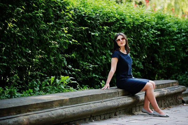 Morena menina de negócios em vestido preto em óculos de sol sentado em b — Fotografia de Stock