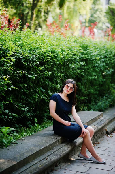 B oturan güneş gözlüğü üzerinde siyah elbise esmer iş kız — Stok fotoğraf