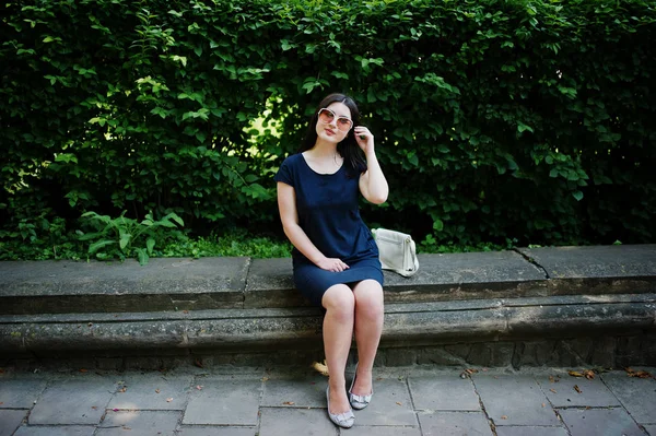 Brünette business girl im schwarzen kleid mit sonnenbrille sitzen bei b — Stockfoto