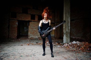 Red haired punk girl wear on black with bass guitar at abadoned  clipart