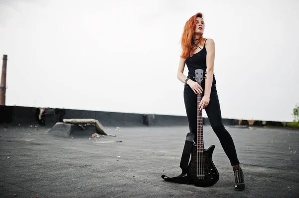 Rojo chica punk pelo desgaste en negro con bajo guitarra en el techo . —  Fotos de Stock
