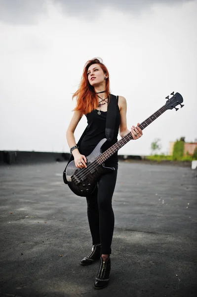 Rojo chica punk pelo desgaste en negro con bajo guitarra en el techo . —  Fotos de Stock