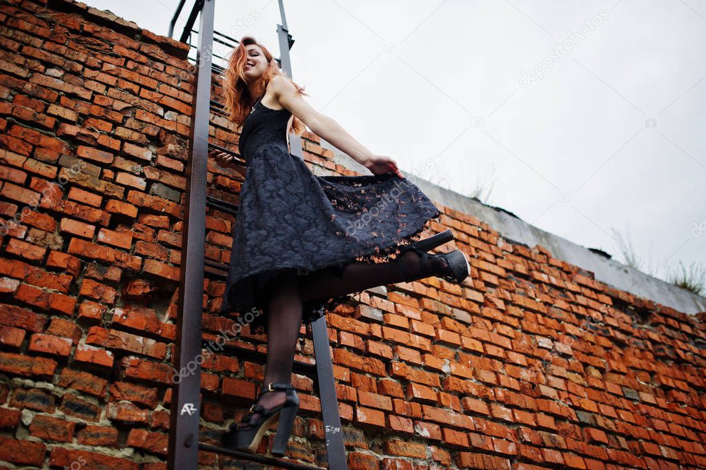 Red haired punk girl wear on black dress at the roof against bri