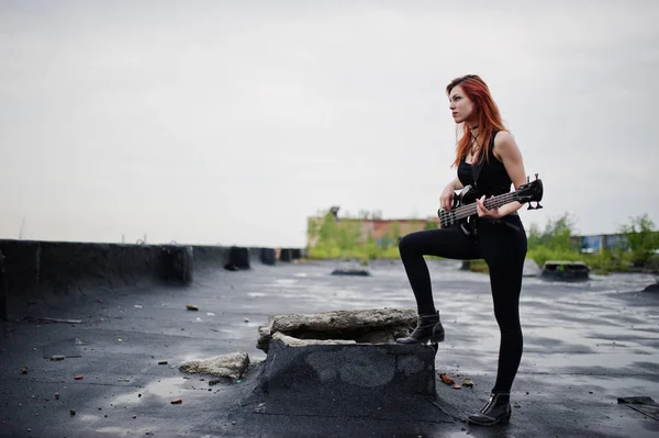 Rojo chica punk pelo desgaste en negro con bajo guitarra en el techo . —  Fotos de Stock