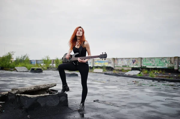 红头发的朋克女孩穿黑色带低音吉他在屋顶上. — 图库照片