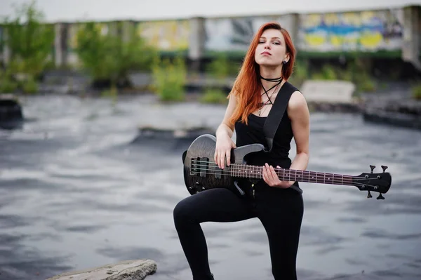 Rojo chica punk pelo desgaste en negro con bajo guitarra en el techo . —  Fotos de Stock