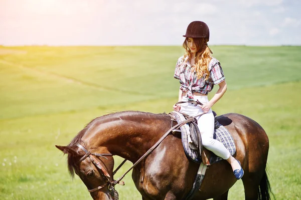 Mooi meisje berijden van een paard op een veld op een zonnige dag. — Stockfoto