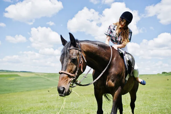 Joven chica bonita montando un caballo en un campo en un día soleado . — Foto de Stock