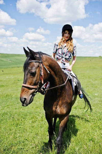 Menina bonita nova montando um cavalo em um campo no dia ensolarado . — Fotografia de Stock