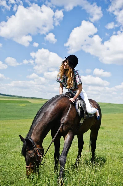 Menina bonita nova montando um cavalo em um campo no dia ensolarado . — Fotografia de Stock