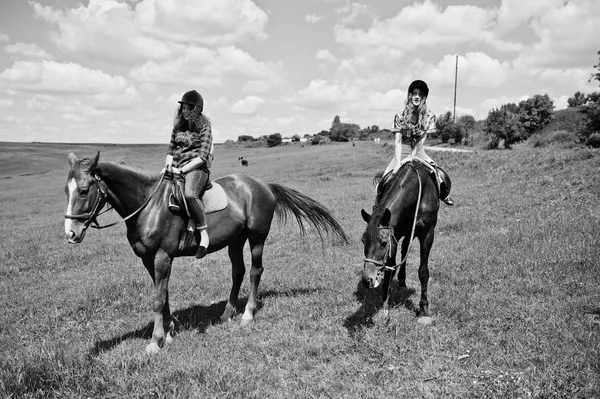 Tow jonge mooie meisjes een paarden rijden op een veld op een zonnige dag — Stockfoto