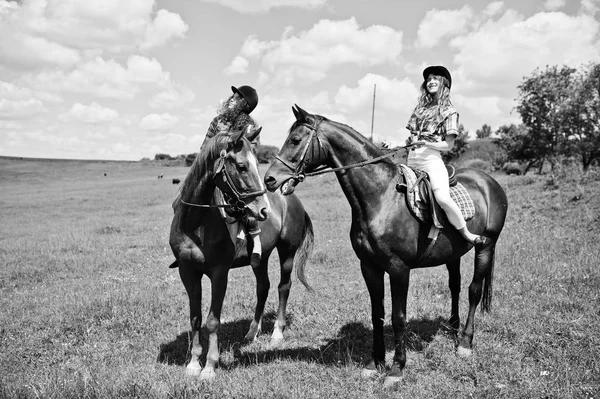 Буксир молодых красивых девушек верхом на лошадях по полю в солнечный день — стоковое фото