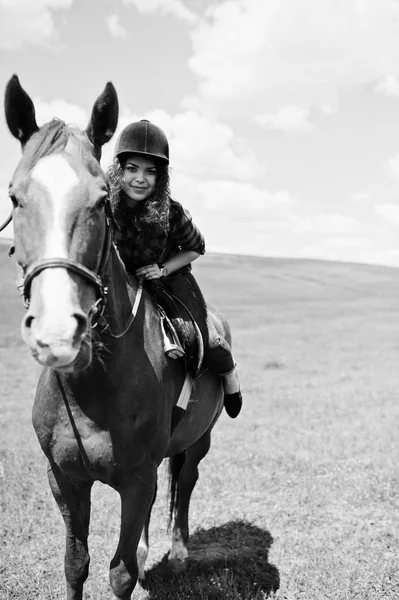 Joven chica bonita montando un caballo en un campo en un día soleado . — Foto de Stock