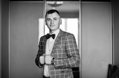 Çok yakışıklı damat odasında poz. Siyah ve beyaz fotoğraf.