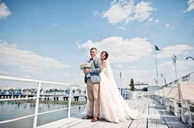 Güzel çift bir iskele üzerinde bir güneşli düğün gününde yürüyüş.